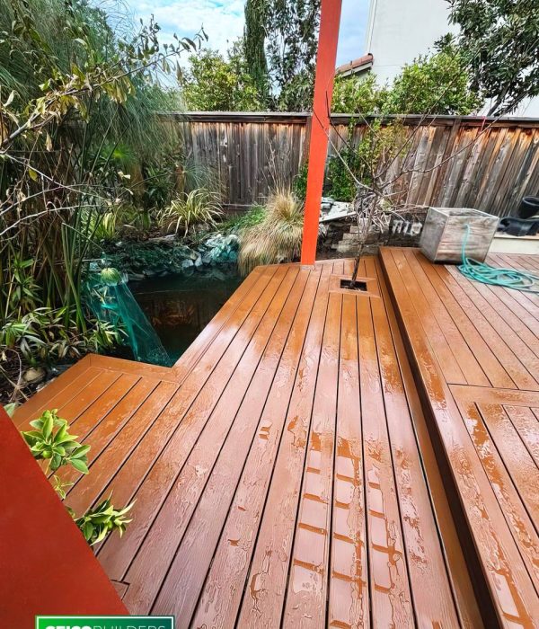 Deck Builder 59 Geico Builders, the #1 deck builder in the Bay Area. Orange toned wood deck with an artificial pond and plants surrounding it.