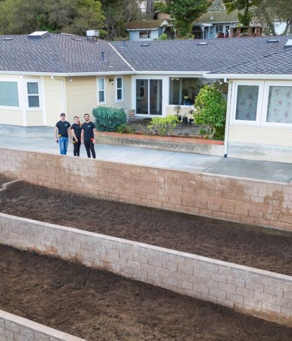 Geico Builders team standing in front of a house with an expertly installed retaining wall