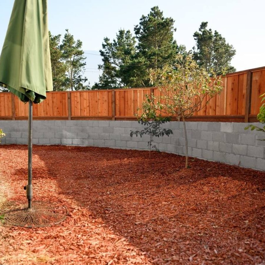 Retaining Wall – Rui Lee 33 Fence on top of a retaining wall in a backyard with a green umbrella