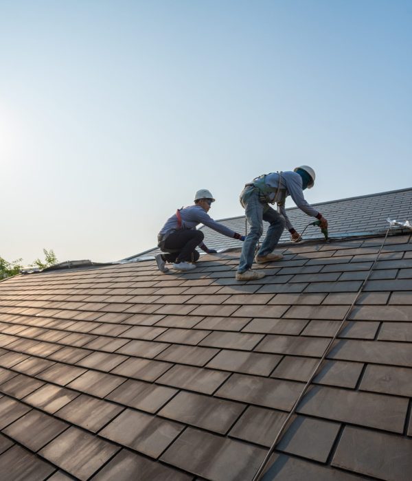 Roofer worker in special protective work wear and gloves,Using pneumatic gun and repair and replace roof tile on top of the new roof.